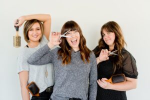 three women posing with scissors and hairbrushes