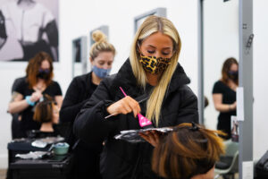 collectiv student applying color to a mannequin's hair